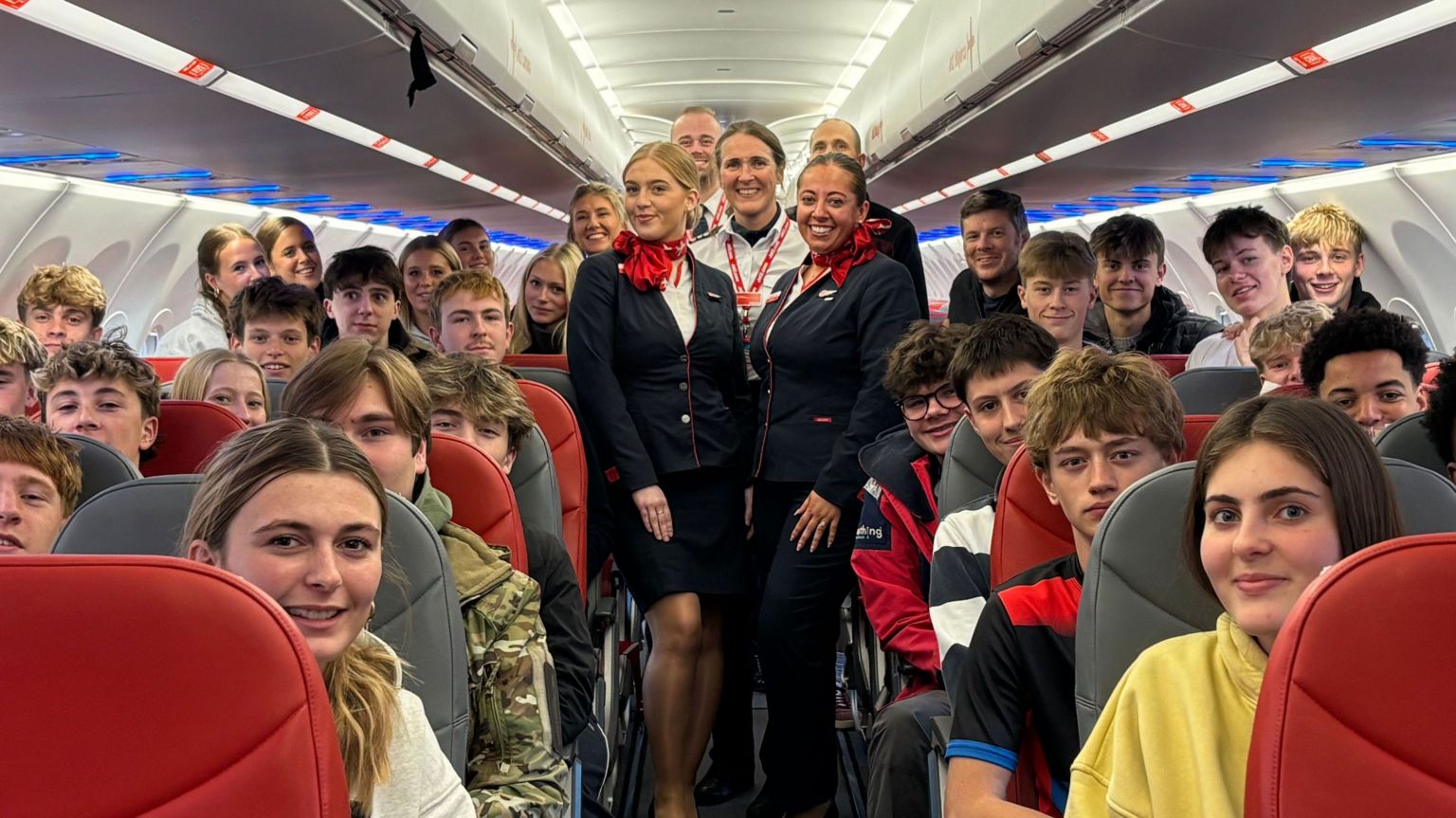 Scholieren in de cabine van een Airbus A321neo van Jet2, met in het gangpad leden van de bemanning in uniform